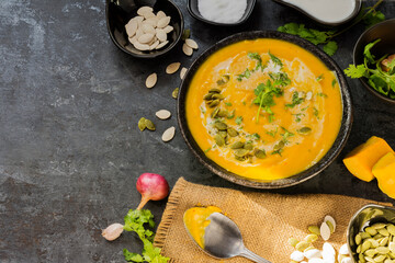 Curry or pumpkin soup with rice served in a ceramic platter on a black background - top view with writing space.