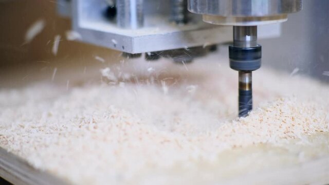 Automatic machine cuts square in wooden piece with drill