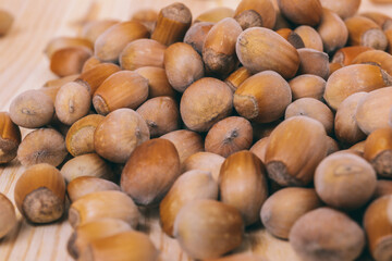 Pile of nuts. Hazelnuts. Whole nuts. Corylus avellana. Macro photo, close up, on wooden table.