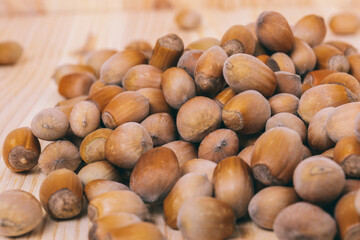 Pile of nuts. Hazelnuts. Whole nuts. Corylus avellana. Macro photo, close up, on wooden table.