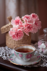 Still-life. A bouquet of pink carnations, a Cup of tea, marshmallows.