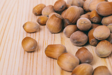 Pile of nuts. Hazelnuts. Whole nuts. Corylus avellana. Macro photo, close up, on wooden table.