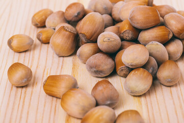 Pile of nuts. Hazelnuts. Whole nuts. Corylus avellana. Macro photo, close up, on wooden table.