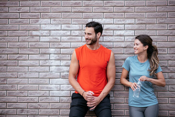 Athletic couple is having a rest after jogging in the city. Happy couple enjoying in the morning..