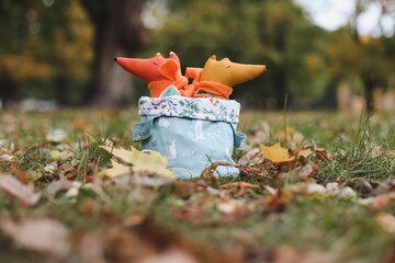 Cute little toys sit in a basket in the autumn garden. Childhood, baby, holiday, people, hobby, emotions concepts
