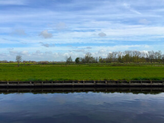 the river near meadow against blue sky in the village of Giethoorn, Holland Netherlands