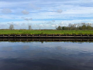 the river near meadow against blue sky in the village of Giethoorn, Holland Netherlands