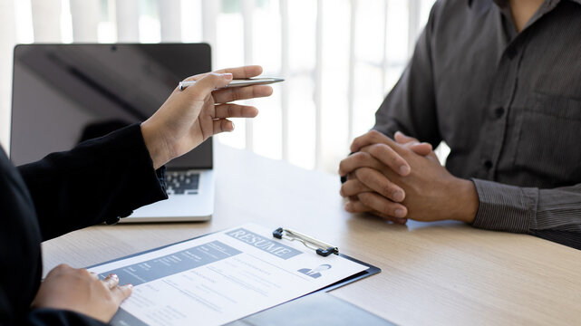 HR head is interviewing a young man's job application in a private room.