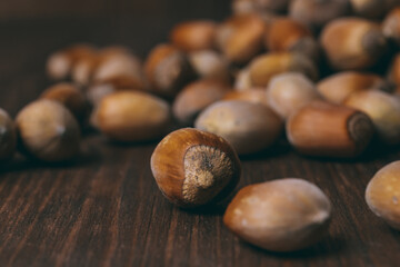 Pile of nuts. Whole nuts. Hazelnuts. Corylus avellana. Macro photo, close up, on dark wooden background.
