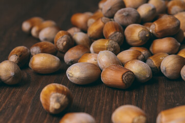Pile of nuts. Whole nuts. Hazelnuts. Corylus avellana. Macro photo, close up, on dark wooden background.