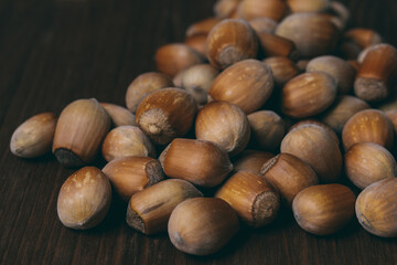 Pile of nuts. Whole nuts. Hazelnuts. Corylus avellana. Macro photo, close up, on dark wooden background.