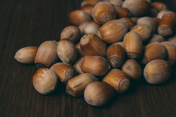 Pile of nuts. Whole nuts. Hazelnuts. Corylus avellana. Macro photo, close up, on dark wooden background.