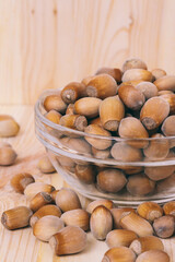 Hazelnuts in glass bowl. Whole nuts. Corylus avellana. Close up, on wooden background.