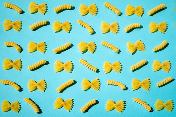 Uncooked curly pasta pattern on blue background. Traditional dry raw macaroni pattern. Nobody