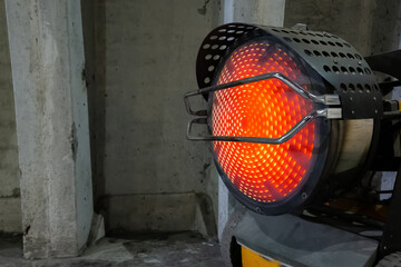 Heavy duty industrial heater blowing hot air in cold building interior. Heat compressor or heat fan propeller, propelling warm air in cold constructions