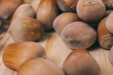 Pile of nuts. Hazelnuts. Whole nuts. Corylus avellana. Macro photo, close up, on wooden table.