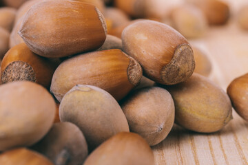 Pile of nuts. Hazelnuts. Whole nuts. Corylus avellana. Macro photo, close up, on wooden table.