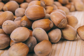 Pile of nuts. Hazelnuts. Whole nuts. Corylus avellana. Macro photo, close up, on wooden table.