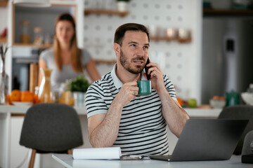 Young man working and talking to the phone. Handsome man working at home