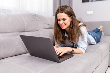 Fototapeta premium Happy pretty woman using laptop sitting on sofa
