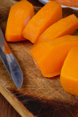 Frozen pieces of pumpkin at the wooden cutting board.