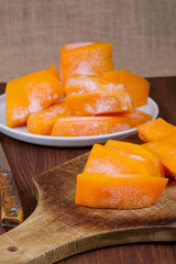 Frozen pieces of pumpkin at the wooden cutting board.