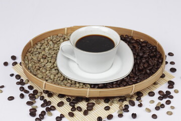 Black coffee is served in a glass cup, which is placed on top of the coffee beans. There are coffee beans that have been roasted and are still fresh beans.