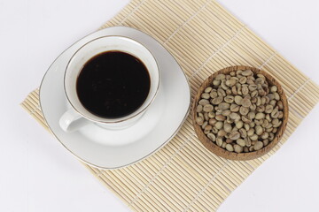 a cup of black coffee juxtaposed with fresh coffee beans on a white background.