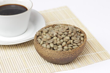 a cup of black coffee juxtaposed with fresh coffee beans on a white background.