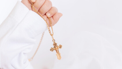 The sacrament of the baptism of a child. The kid is holding a cross. Selective focus.