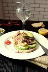 Gluten free food. Buckwheat crispbread sandwiches with avocado and tuna paste with olives and chilly pepper on wooden background. Vertical foto