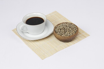 a cup of black coffee juxtaposed with fresh coffee beans on a white background.