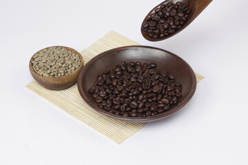 coffee beans that have been roasted and dropped from a spoon, juxtaposed against fresh coffee beans, to show the different color of the coffee beans.