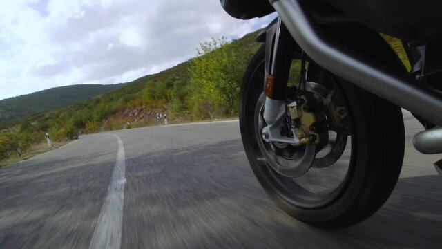 Motorcycle ridind on a road in nature. Close up wheel on a bumpy asphalt road. Speed up video