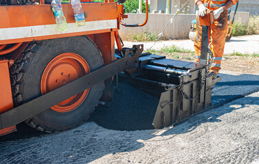 New Road - Pavement machine laying fresh asphalt or bitumen on top of the gravel base during highway construction