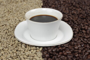 Black coffee is served in a glass cup, which is placed on top of the coffee beans which are arranged neatly to form a heart.