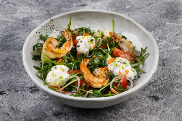Salad with shrimp, arugula ,cucumber and onion on a white plate