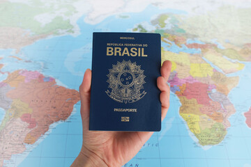 Fototapeta na wymiar Hand holding a Brazilian passport with a map background