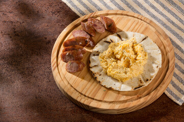 Tasty Colombian breakfast; White corn arepa with chorizo and scrambled eggs.