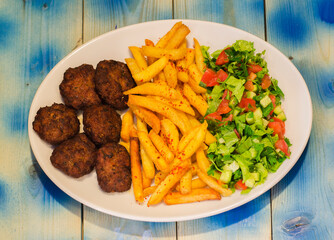 Meatball plate, french fries and salad, blue wooden background
