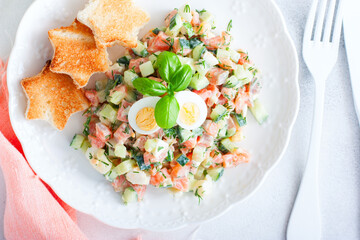 Salad with red fish, fresh cucumbers and herbs, egg with white bread toast, selective focus, top view