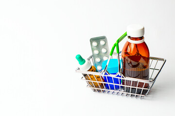 Remedy for colds and flu in a grocery basket on a white background.Tablets, nasal drops, rubbing...