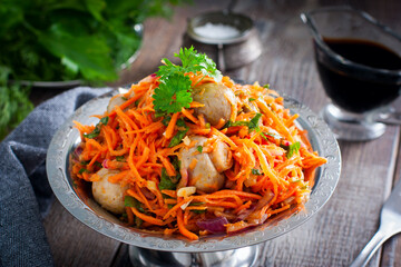 Spicy salad with champignons and Korean carrots in a metal vase, selective focus