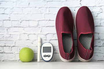  diabetic measurement tools, shoe and apple on table 