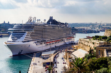 Mega modern MSC cruiseship or cruise ship liner in port of Valletta, Malta island with panoramic...