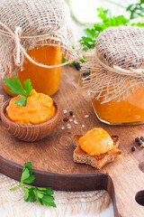 Homemade squash caviar in glass jars, gravy boat and on toast on wooden board, selective focus