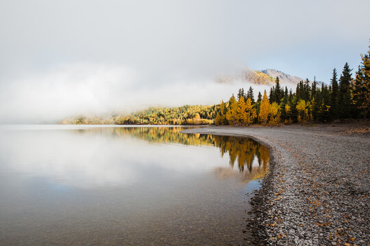 autumn landscape with still lake, clouds and blue sky