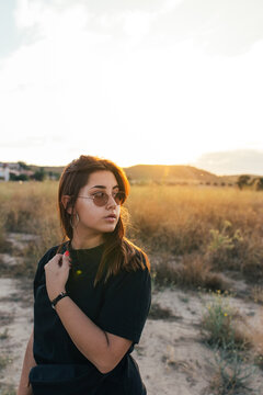 Teenager in sportswear and sunglasses at sunset in the countryside
