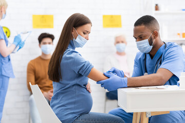Fototapeta premium Pregnant Woman In Mask Getting Vaccinated Against Covid-19 In Hospital