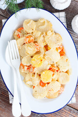 Baked potatoes with carrots in the oven on a white dish, selective focus